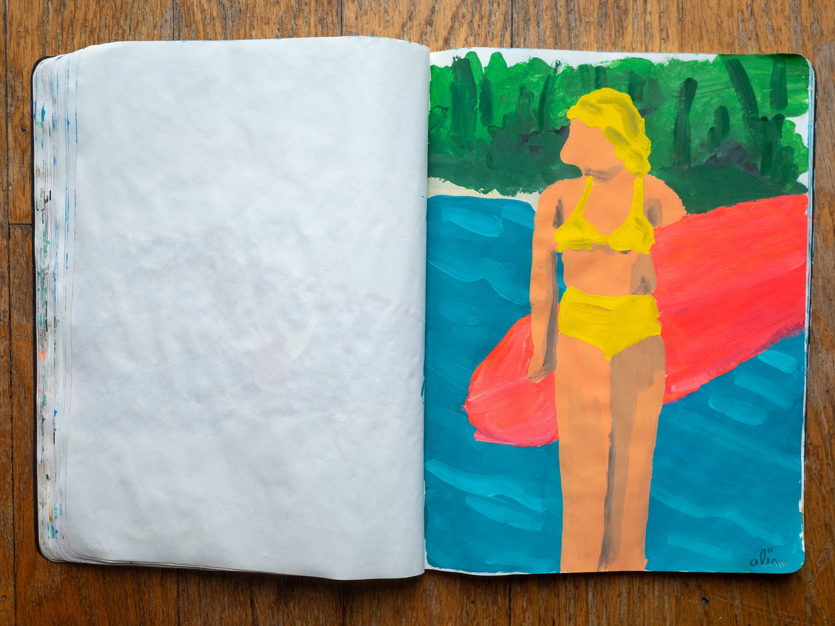 Drop 07 sketch 02 by Alimo in the open Moleskine sketchbook, painted on the right page only: a woman in a yellow bikini holding a pink surfboard in front of green trees
