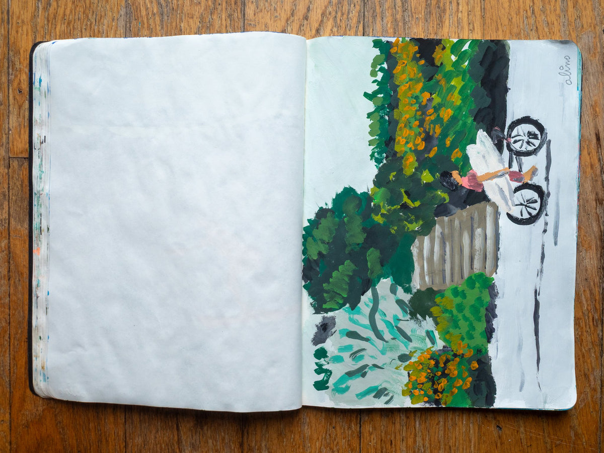Drop 07 sketch 07 by Alimo in the open Moleskine sketchbook, painted on the right page only: a bike with a surfboard parked by a leafy garden fence