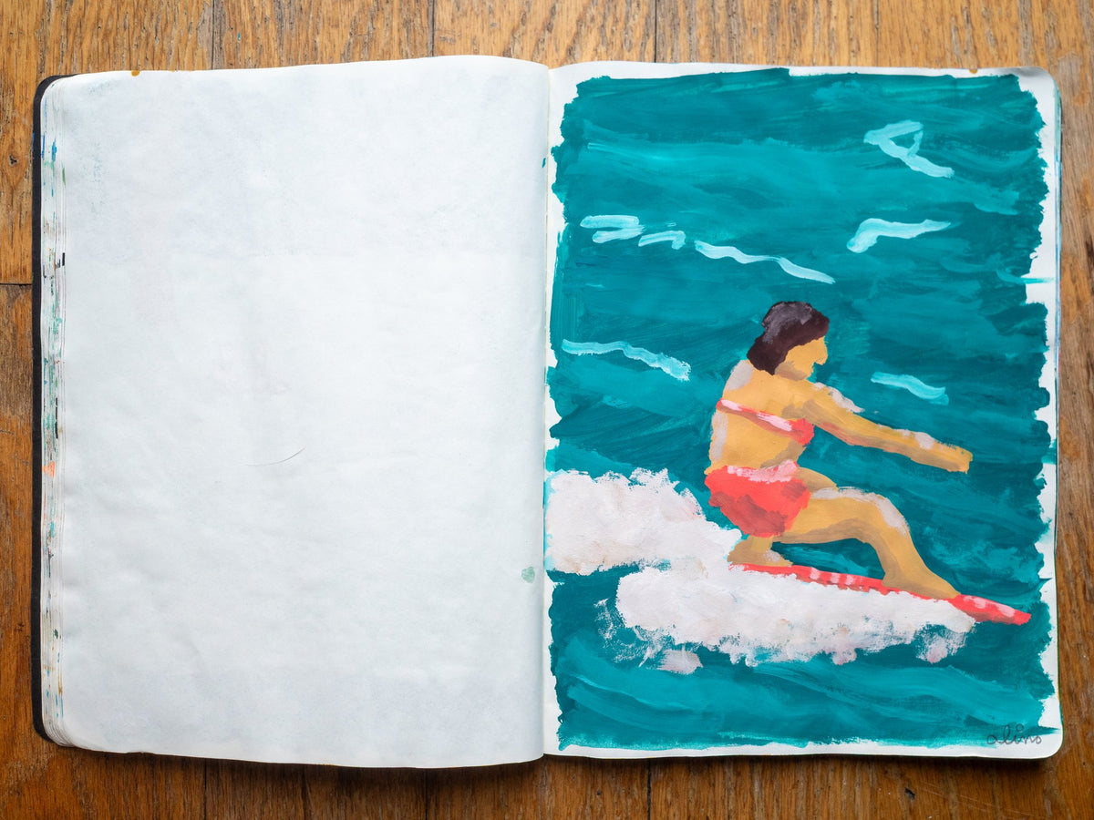 Drop 07 sketch 10 by Alimo in the open Moleskine sketchbook, painted on the right page only: a surfer in a pink swimsuit riding a board across teal water